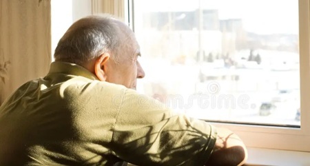 Lonely old man staring out the window